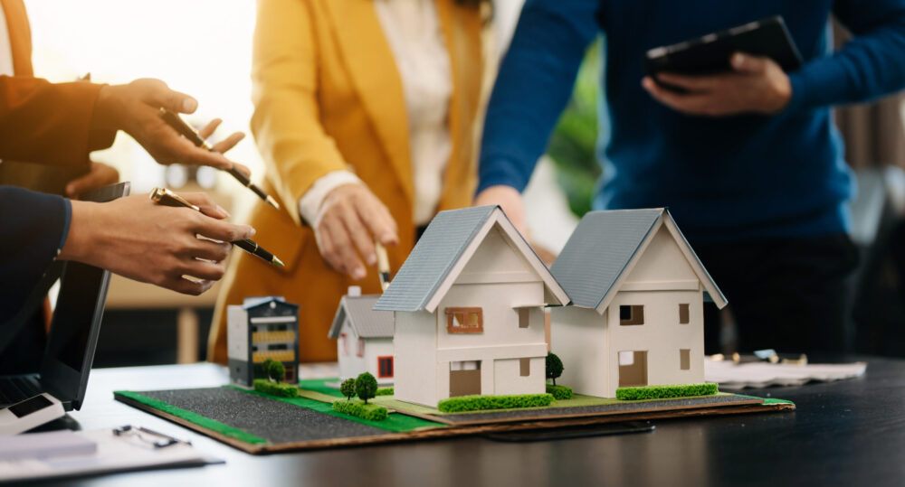 balancing the property sector The real estate agent is explaining the house style to see the house design and the purchase agreement.Wooden house at modern office